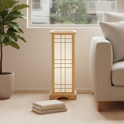 Elegant japanese style lamp with geometric shoji panels positioned on wooden floor near window and stacked books in bright minimalist interior