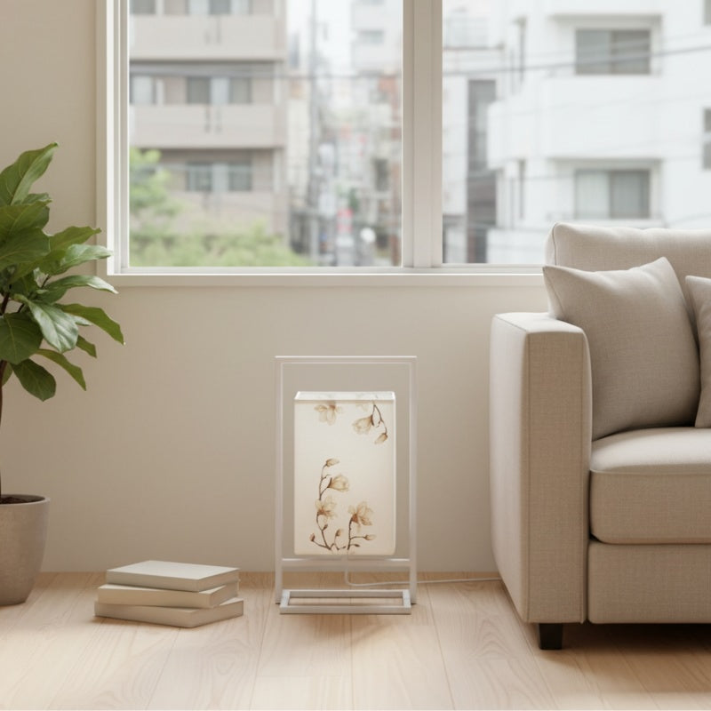 Minimalist japanese table lamp modern design with botanical pattern on white shade beside beige sofa near bright window in contemporary living room