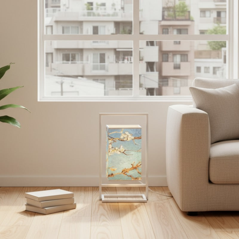 Charming japanese table lamp style with cherry blossom artwork on blue fabric shade glowing beside modern sofa in minimalist apartment setting