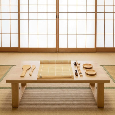 Simple kit maker sushi with bamboo rolling mat, wooden paddles and chopsticks on traditional tatami table