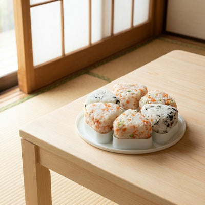 Homemade kit onigiri with six perfectly shaped rice balls topped with sesame and nori on white ceramic plate