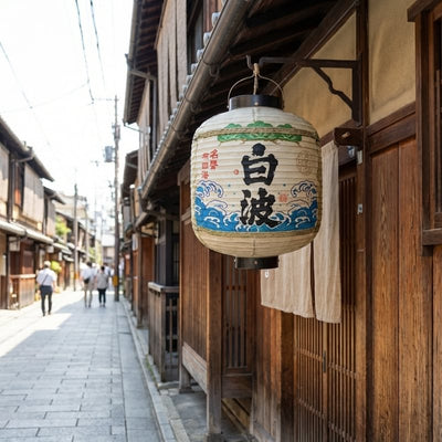 Authentic lantern japanese lamp with wave patterns hanging outside traditional wooden building on historic district street in bright daylight