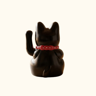 Rear view of a black lucky Maneki Neko cat statue with a raised paw, glossy finish and red collar.