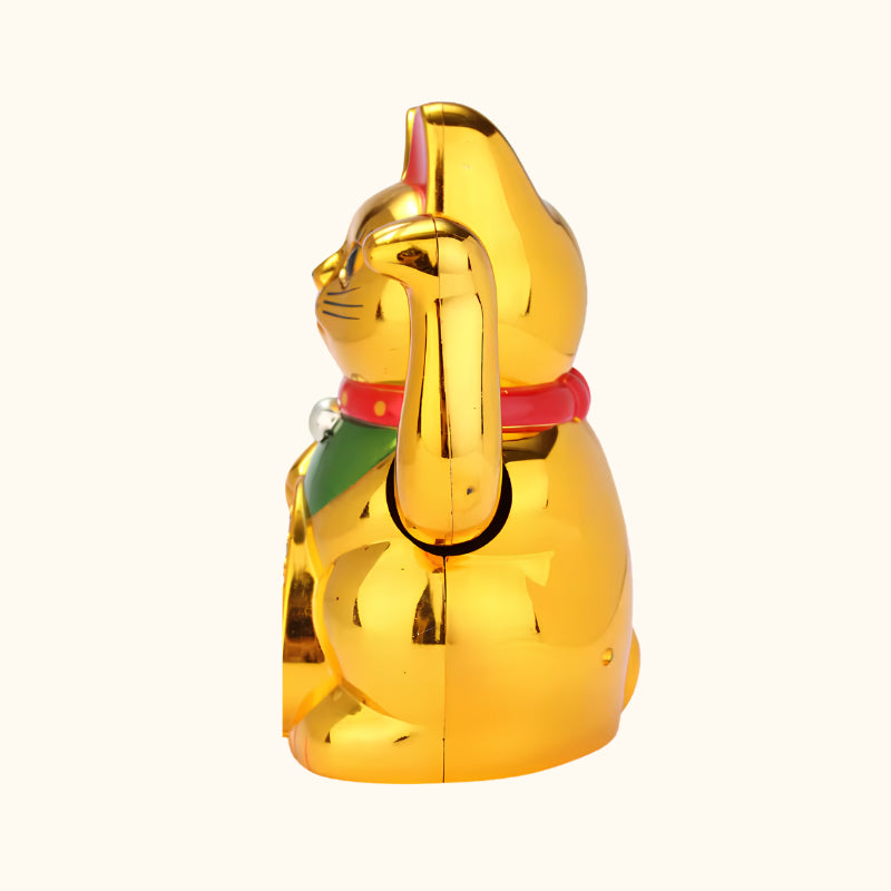 Side profile of a gold Maneki Neko cat statue featuring a raised waving paw, traditional red collar and green bib.
