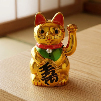 Shiny maneki neko gold cat with waving paw and fortune kanji displayed on wooden table in warm Japanese interior with natural light