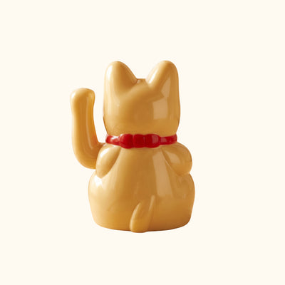 Rear view of a golden Maneki Neko Japanese figurine featuring a raised paw, red collar and curved tail.