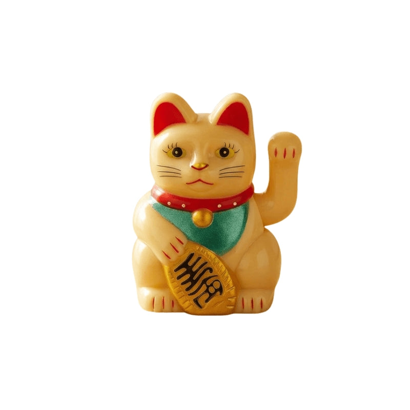 Bright yellow maneki neko japanese figurine with red ears and green collar holding golden coin on neutral white background