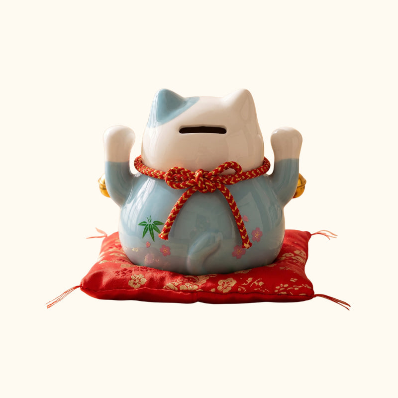 Blue Maneki Neko Lucky Cat Japanese ceramic money box, rear view with raised paws and red cushion