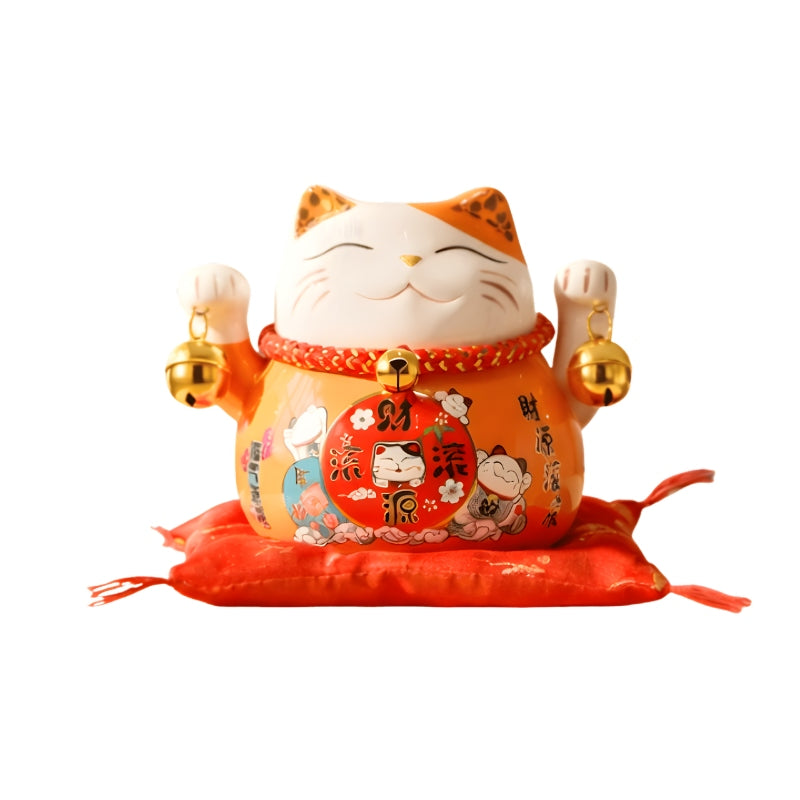 Fortune bringing maneki neko lucky japanese figure with decorative patterns and both paws raised displayed on red silk cushion against white backdrop