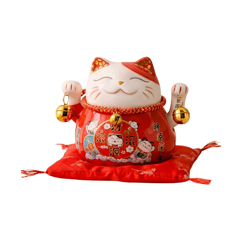 Auspicious maneki neko statue japanese style with prosperity kanji and both welcoming paws raised displayed on red ceremonial cushion against white