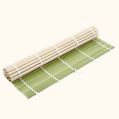 Traditional mat rolling sushi in natural bamboo and green colors shown partially rolled on white background