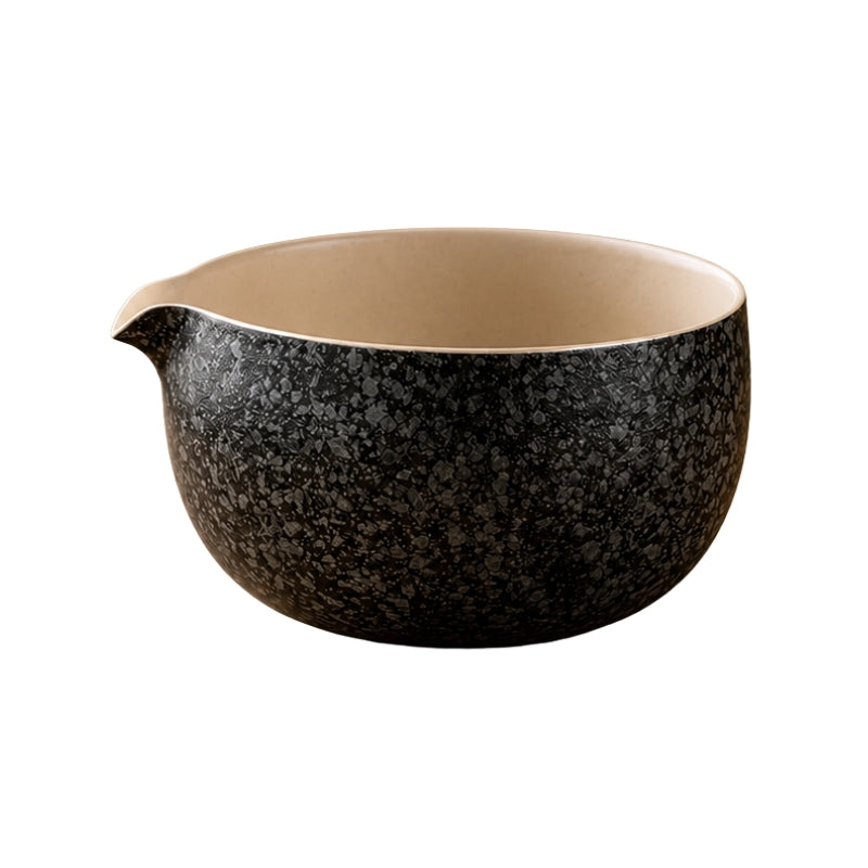 Matcha bowl chawan with black speckled exterior, cream interior and small pouring lip on white background