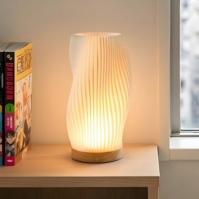 Modern japanese lamp white ribbed twisted shade with warm golden glow on wooden shelf next to manga bookshelf near window