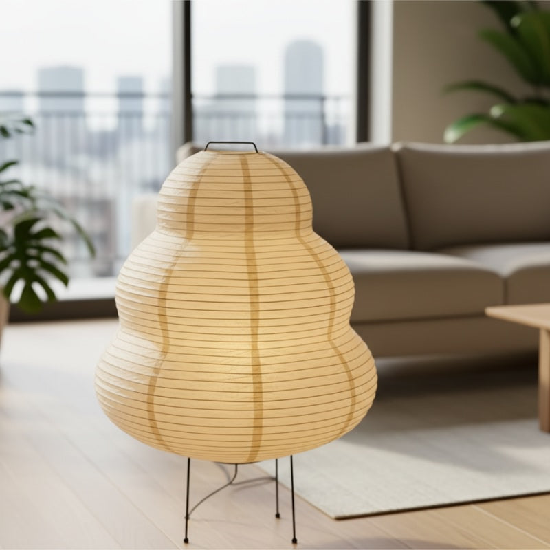 Paper floor lamp japanese style with glowing gourd shaped washi shade on black tripod base illuminating traditional tatami room with shoji screen at night