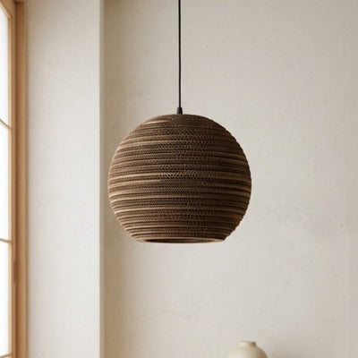 Pendant light Japanese style round cardboard sphere hanging in minimalist corner with white walls and natural wood accents