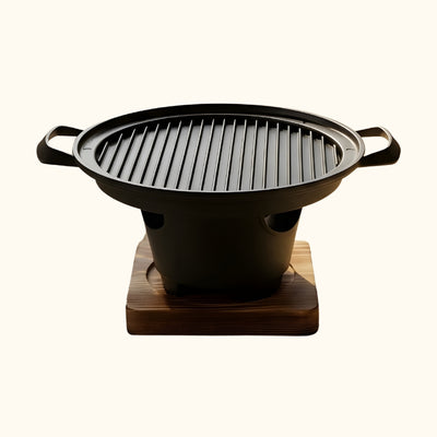 Plate Japanese style barbecue with round ridged grilling surface and black ceramic burner bowl on natural wood stand