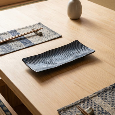 Minimalist plate of sushi blue with linear pattern on natural wood table with geometric table runner