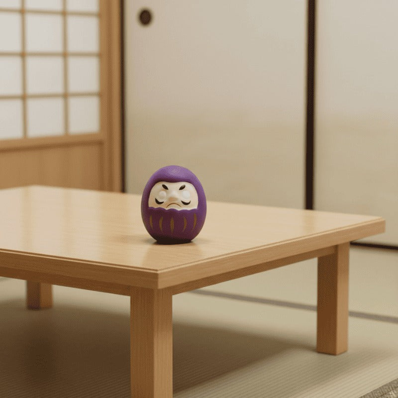 Purple daruma japanese wish doll with gold accents sitting on wooden table in serene traditional interior with sliding doors