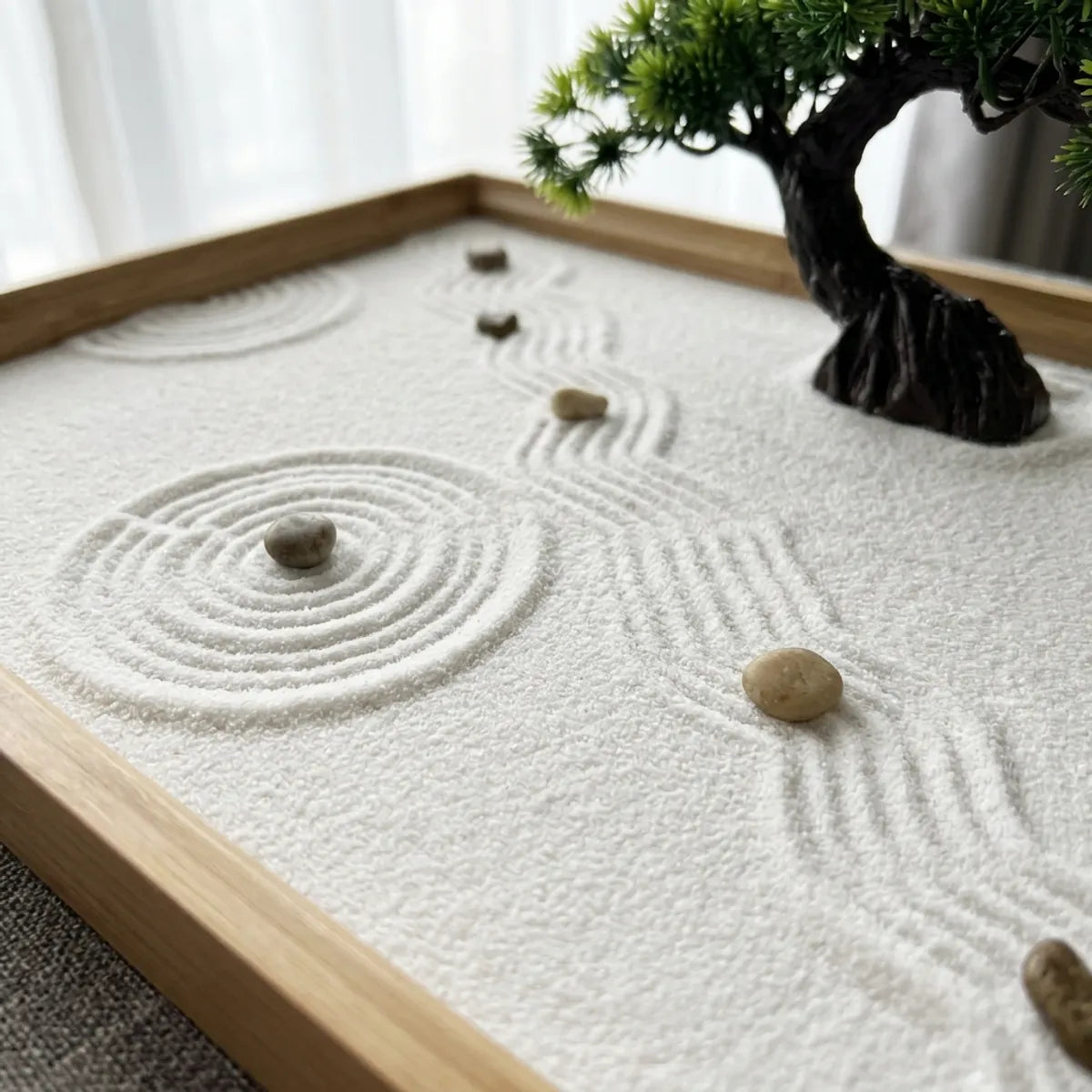 Close-up of the raked white sand showing fine parallel wave lines and concentric circle patterns around the pebbles and rock base.