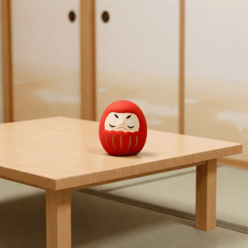 Traditional red daruma japanese doll on wooden table beside sliding door in authentic tatami room with natural light