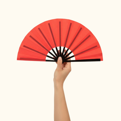 Beautiful red fan japanese with gradient coral shades held delicately in hand against minimalist white background highlighting fine details