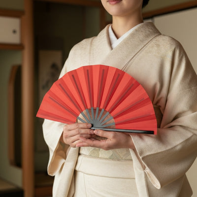 Authentic red japanese fan held by person wearing beige kimono in traditional tatami room with warm natural afternoon light