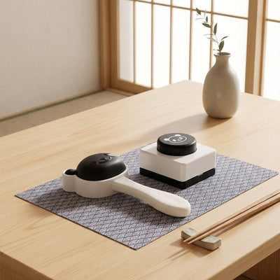 Elegant rice sushi maker with black panda design and white ceramic base on geometric patterned table runner