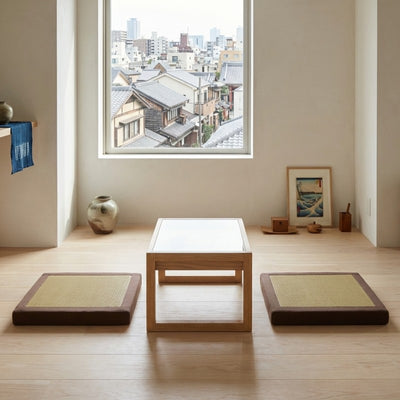 Seating japanese cushion duo with beige tatami surface beside wooden table near window overlooking traditional rooftops with ukiyo-e art