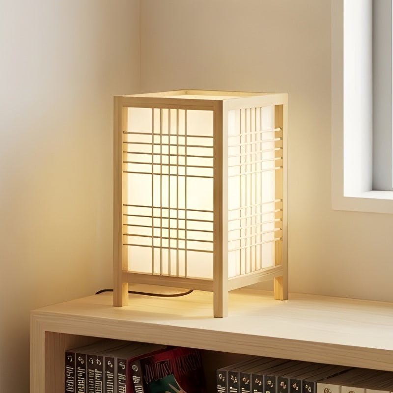 Minimalist shoji lamp in natural pine wood casting soft warm light on shelf above book collection