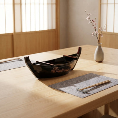 Sushi boat black lacquered vessel with golden ocean wave design on natural wood table with fabric placemat and chopsticks