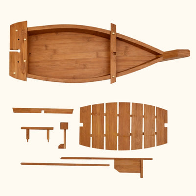 Handcrafted sushi boats focus showing assembled bamboo boat tray with side paddles and disassembled components including slatted deck panel chopsticks and support stands on white background