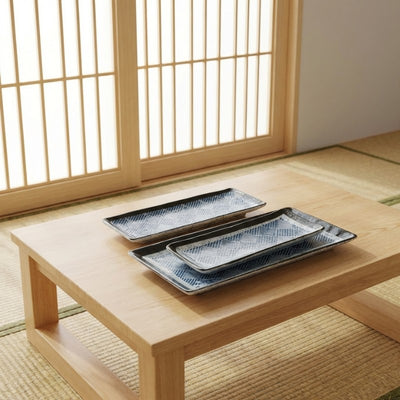 Multiple sushi decoration plate pieces arranged on low Japanese table with shoji screen background