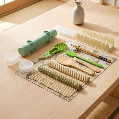Essential sushi kit making tools arranged on natural wood surface with rice paddle and bamboo rolling mat