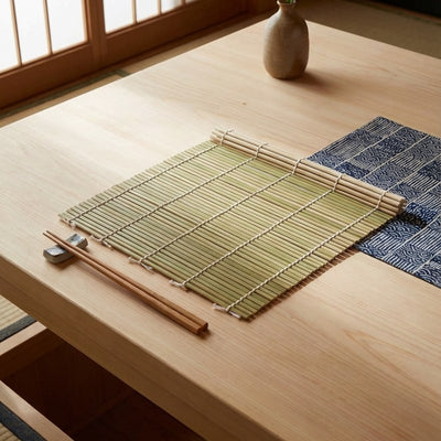 Authentic sushi mat rolling displayed flat on wooden table with blue seigaiha wave pattern fabric