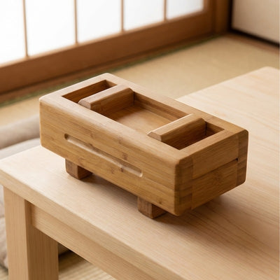 Close-up of sushi mold in warm-toned bamboo with open press cavity and short footed base on low chabudai table in traditional Japanese tatami room with shoji window