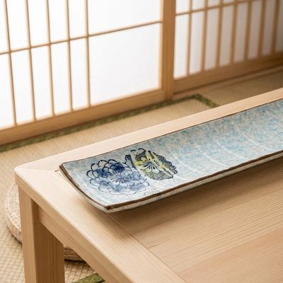 Elegant sushi plate ceramic with handpainted chrysanthemum decorations on natural wood surface in Japanese interior
