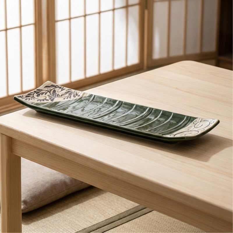 Long rectangular sushi plate with green glaze and botanical decorations on wooden chabudai table