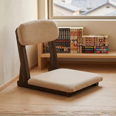 Tatami chair with beige linen upholstery on light wood flooring near shelf with manga collection and window
