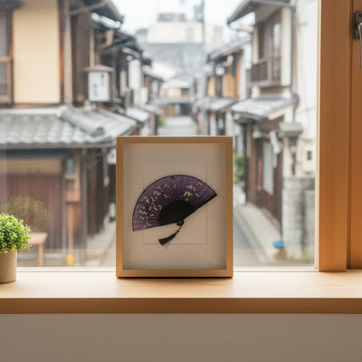 Elegant vintage japanese fan black with white sakura and butterflies in wooden frame on windowsill with historic Kyoto street view in winter