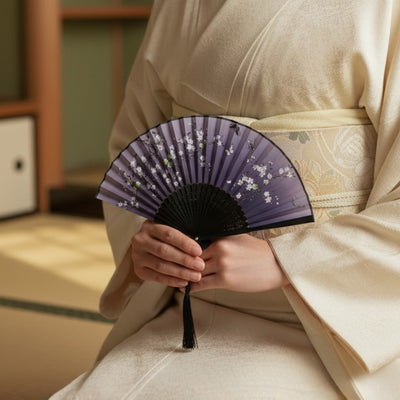 Vintage japanese fan with twilight purple design white blossoms and butterflies held by person in cream kimono in traditional tatami room