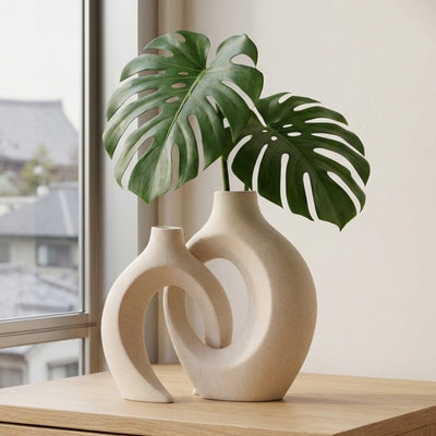 Modern vintage japanese vase set with circular openings holding monstera leaves by window with urban view