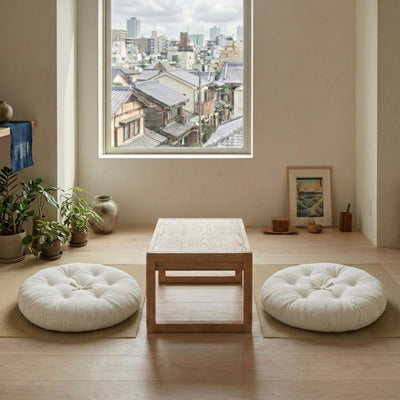 Placed on either side of a low table with a city view, these white cushions for meditation sit on woven tatami mats