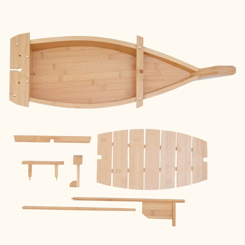 Natural wood sushi boat focus displaying light bamboo serving tray in boat shape with all disassembled parts including slatted panel chopsticks and mast stands on clean white background
