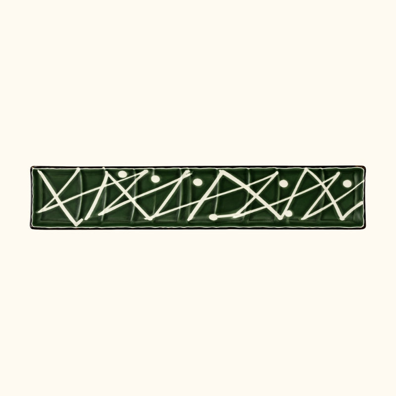 Close-up of zigzag plate sushi featuring abstract geometric white lines on hunter green ceramic surface